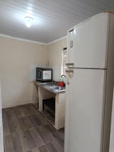 a kitchen with a refrigerator and a table with a microwave at hospedagem da rosa in Morretes