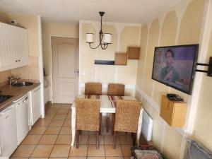 a kitchen with a table with chairs and a tv on the wall at Residence de bordaberry in Urrugne +11 photos