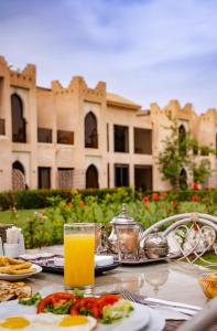 a table with a plate of food and a glass of orange juice at Palais Nouhass in Marrakesh