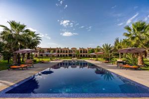 a pool at a resort with umbrellas and chairs at Palais Nouhass in Marrakesh