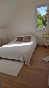 a white bedroom with a large bed with a window at pavillon en pleine nature in Brains-sur-Gée