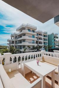 a white table and chairs on a balcony with a building at Parid Apartments in Sarandë
