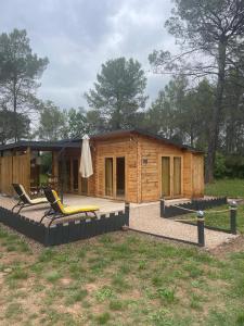 a log cabin with two lounge chairs in front of it at Chalet Le Luc - Casa Zenitude in Le Luc