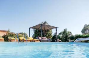 a large swimming pool with a pavilion in the background at Chalet Le Luc - Casa Zenitude in Le Luc