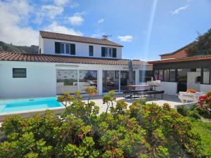 a villa with a swimming pool and a house at Casa da Uva-Mosteiros Vineyards House-Heated swimming-pool in Mosteiros
