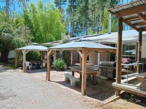 a patio with benches and umbrellas and a grill at Eco Lodge Pakowhai in Hastings