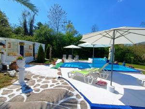 a swimming pool with an umbrella and chairs and a pool at Spa Apartment Expo 27 in Brestovik