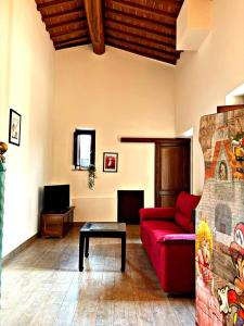 a living room with a red couch and a table at La Casa di Nonna Iolanda in Gualdo Cattaneo