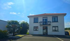 a white house with a balcony and a parking lot at DIAG Appartement 3 Chambres in Commequiers