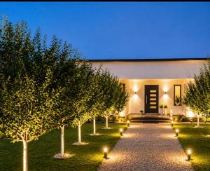 a garden with trees and lights in front of a building at Relax Villa with Pool in Bihać