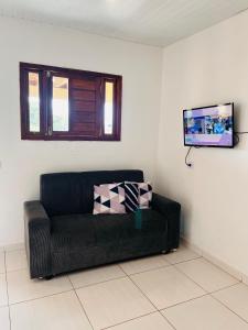 eine schwarze Couch in einem Wohnzimmer mit einem Flachbildfernseher in der Unterkunft Pousada Aconchego Sol e Mar in Maragogi + 46 Fotos