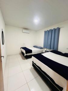 zwei Betten in einem Zimmer mit blauen Vorhängen in der Unterkunft Pousada Aconchego Sol e Mar in Maragogi