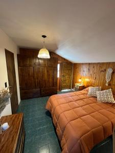 a bedroom with a large bed with wooden walls at Rincón Las Hiedras in Chacras de Coria