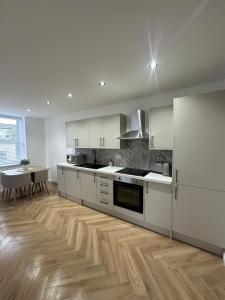 a kitchen with white cabinets and a wooden floor at Modern Two- bedroomed flat in Wick, Caithness in Wick