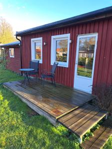 eine Terrasse mit zwei Stühlen und einem Tisch vor einem roten Haus in der Unterkunft Öjavad in Svängsta