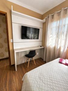 a bedroom with a tv and a desk with a chair at Casa com Piscina e Jacuzzi, Próxima da Praia Brava in Itajaí