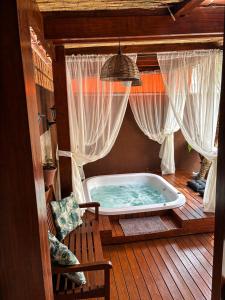 a jacuzzi tub on a wooden deck with curtains at Casa com Piscina e Jacuzzi, Próxima da Praia Brava in Itajaí +17 photos