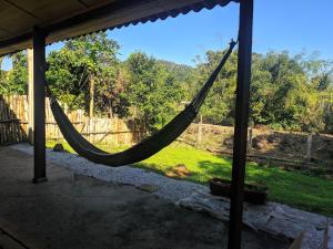 a hammock in a porch with a view of a yard at Chácara Caminho do Rio in Morretes