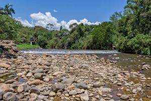 a river with rocks and trees in the background at Chácara Caminho do Rio in Morretes