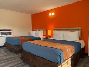 two beds in a hotel room with orange walls at Ponca Motel in Abilene