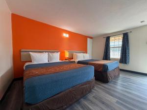 a hotel room with two beds and an orange wall at Ponca Motel in Abilene +21 photos