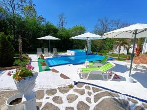 a patio with a pool and chairs and umbrellas at Spa Apartment Expo 27 in Brestovik
