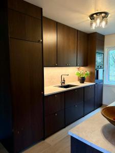 a kitchen with dark wood cabinets and a sink at Flott 4-roms leilighet til leie in Trondheim