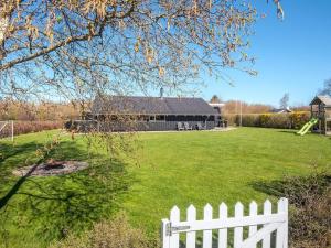 a white fence in front of a yard with a building at 8 person holiday home in Sydals in Neder Lysabild