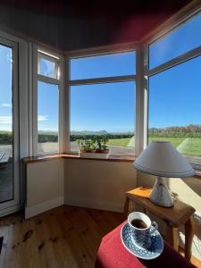 ein Zimmer mit Fenstern und einem Tisch mit einer Tasse Kaffee in der Unterkunft Three Sisters in Dingle