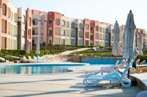 a resort with a swimming pool with chairs and umbrellas at شاليه 2 غرفه in Marsa Alam
