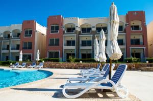 a resort with chairs and umbrellas and a swimming pool at شاليه 2 غرفه in Marsa Alam