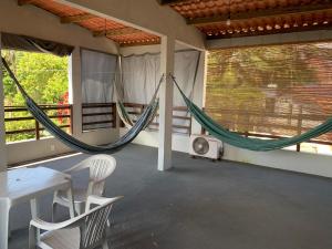 two hammocks in a room with a table and chairs at Apartamento com Terraço na Gamboa do Morro in Cairu