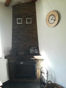 a fireplace in a living room with a clock on the wall at Casa da Encosta - Piódão in Piódão