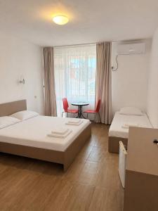 a bedroom with two beds and a table and chairs at Siana House in Ravda