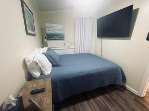 a small bedroom with a bed and a flat screen tv at Boltons Bungalow Casa Del Mar in Galveston +14 photos