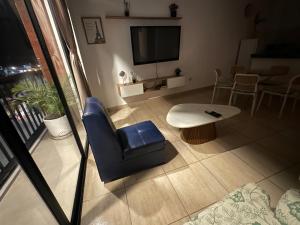 a living room with a blue chair and a tv at Lindo Departamento con Terraza Vista al Mar in Pimentel