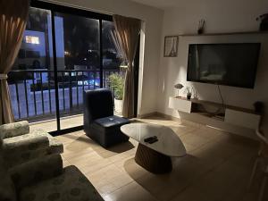 a living room with a tv and a chair and a table at Lindo Departamento con Terraza Vista al Mar in Pimentel