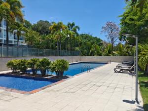 a swimming pool with palm trees in front of a building at Apartamento frente al mar El Palmar in Las Palmeras