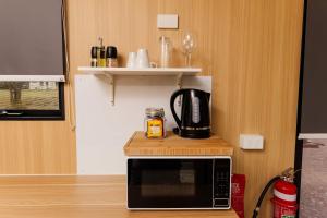 a microwave with a coffee maker on top of it at The Tiny Chalet by Tiny Away in Bromfleet +18 photos