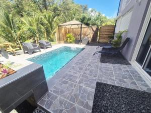 a swimming pool in a yard with chairs and a table at L'Escale du Plaisir in Grande Savane +7 photos