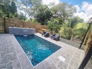 a pool with two chairs and a bench in a yard at L'Escale du Plaisir in Grande Savane