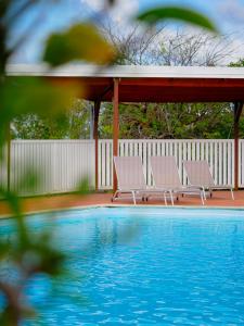 two chairs sitting under a gazebo next to a swimming pool at Petite Ancre in Le Gosier