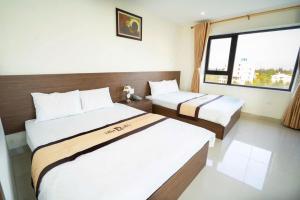 a hotel room with two beds and a window at KHÁCH SẠN THĂNG LONG 2 FLC SẦM SƠn in Binh Tân