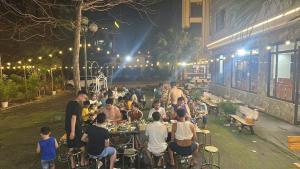 a group of people sitting at tables outside a restaurant at night at KHÁCH SẠN THĂNG LONG 2 FLC SẦM SƠn in Binh Tân