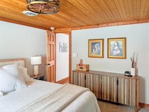 a bedroom with a bed and a wooden ceiling at Ultimate Hayward Trailhead Cabin - Base Camp 77 in Hayward
