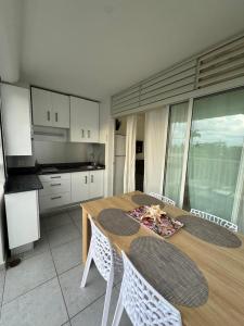 a kitchen with a wooden table with chairs and a dining room at Le Cocon Bleu in Le Moule