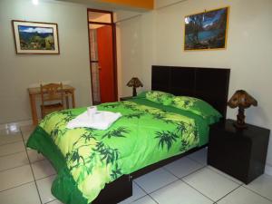 a bedroom with a bed with a green comforter at Hotel Selena 1 in Huaraz