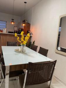 a dining room table with yellow flowers in a vase at New House Temporada in João Pessoa +7 photos