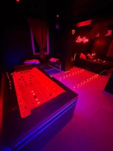 a room with red and purple lights and beds at La nuit éternelle in Amilly
