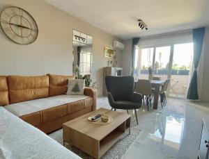 a living room with a couch and a clock on the wall at Apartman Green Oaza in Vrbas